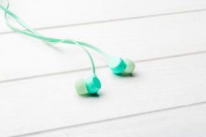 Digital light-blue earbuds on the minimalistic table, macro with